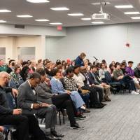 rows of people seated, two women seated on stage for presentation